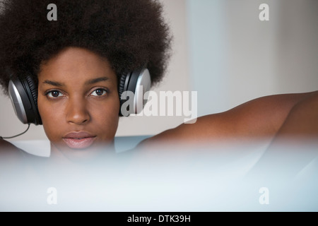 Donna ascoltando le cuffie nella vasca da bagno Foto Stock