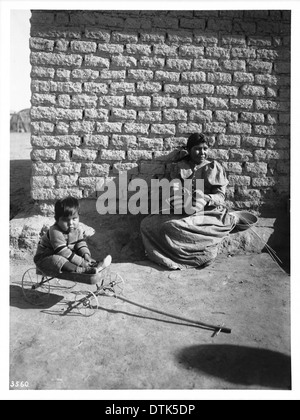 Una donna indiana Pima, accompagnata dal suo giovane figlio, tesseva un cesto a Gila Crossing, Arizona, intorno al 1900, raffigurante l'artigianato tradizionale dei nativi americani. Foto Stock