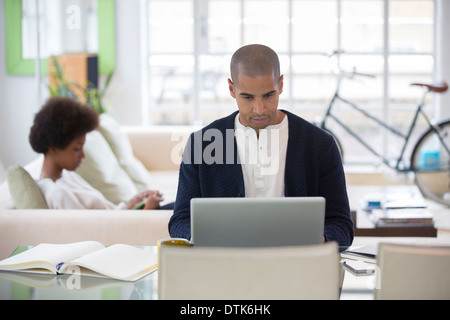 Uomo con notebook alla scrivania in soggiorno Foto Stock