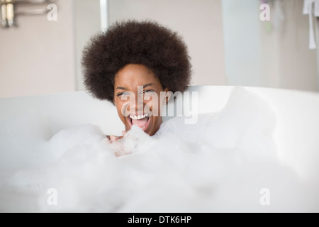 Donna che ride in bagno di bolle Foto Stock