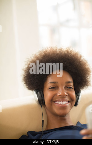 Donna in ascolto delle cuffie sul divano Foto Stock