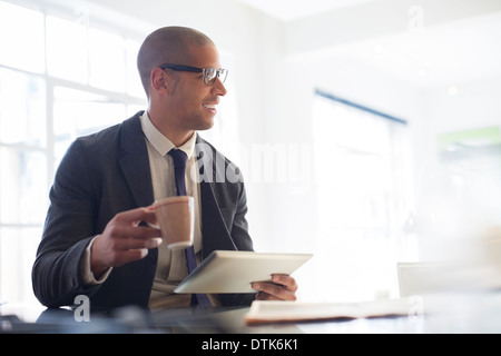 Imprenditore con tavoletta digitale e di bere il caffè Foto Stock