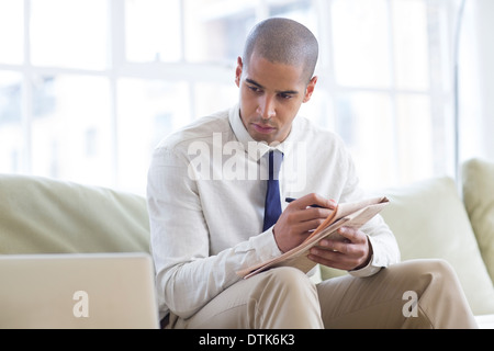 Imprenditore rendendo note dal computer portatile sul divano Foto Stock
