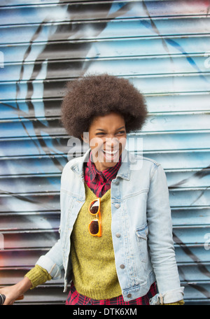 Donna che ride nella parte anteriore del muro di graffiti Foto Stock