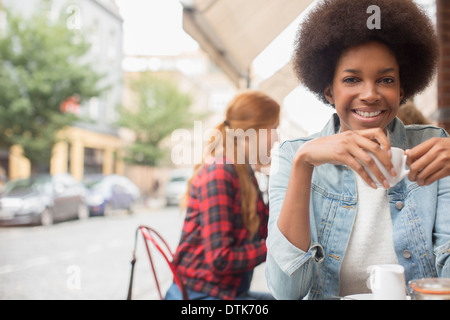 Donna di bere caffè al cafè sul marciapiede Foto Stock