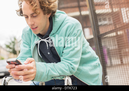 Uomo con telefono cellulare in bicicletta Foto Stock