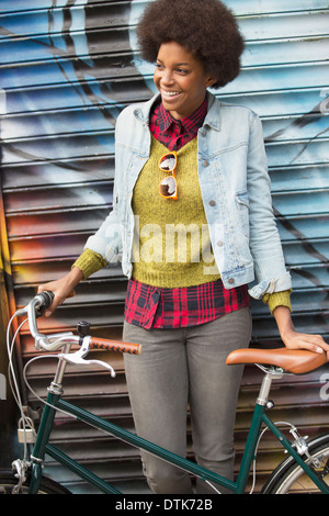 Donna bicicletta di contenimento nella parte anteriore del muro di graffiti Foto Stock