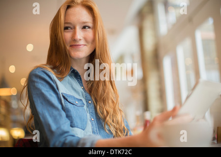 Donna che utilizza digitale compressa in cafe Foto Stock