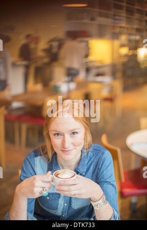 Donna di bere tazza di caffè nella caffetteria Foto Stock