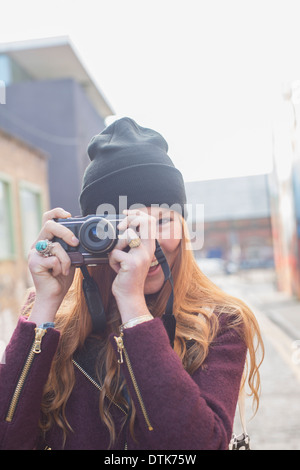 Donna che utilizza la fotocamera su una strada di città Foto Stock