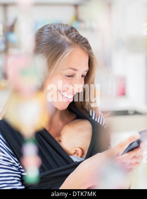 Madre con bambino tramite telefono cellulare Foto Stock