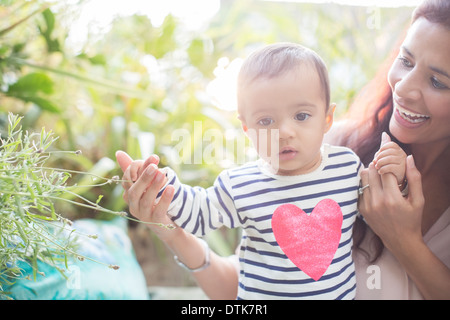 Madre aiutare baby boy a piedi all'aperto Foto Stock