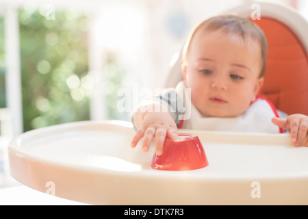 Baby boy eating in sedia alta Foto Stock