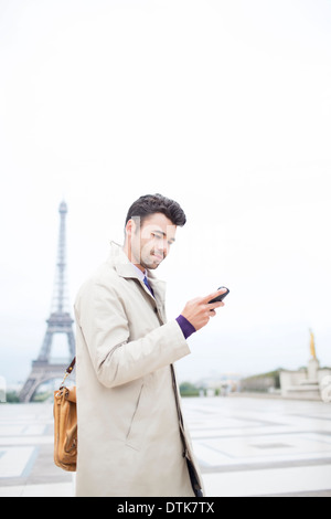 Imprenditore tramite telefono cellulare dalla Torre Eiffel, Parigi, Francia Foto Stock