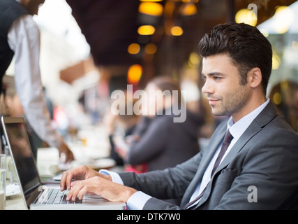Uomo d affari con computer portatile presso cafè sul marciapiede Foto Stock