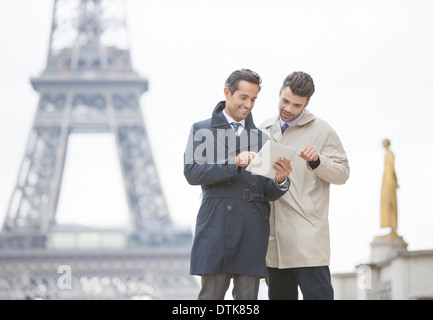 Imprenditori con tavoletta digitale vicino alla Torre Eiffel, Parigi, Francia Foto Stock