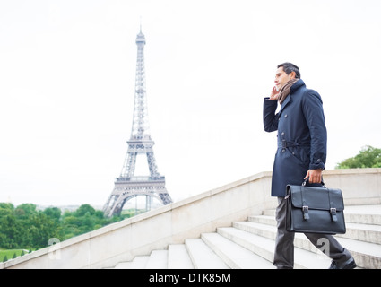 Imprenditori sul cellulare su passi vicino alla Torre Eiffel, Parigi, Francia Foto Stock