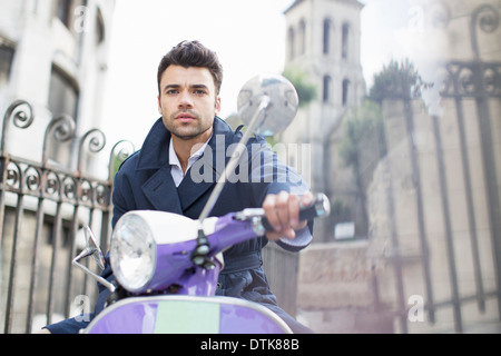 Uomo alla guida di uno scooter su strada di città Foto Stock