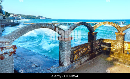 Tempesta di mare, rovinato pier e schizzi di surf davanti (Mar Nero, Bulgaria, vicino a Varna). Foto Stock