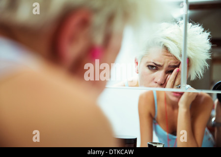 Hungover donna esaminando se stessa in specchio Foto Stock