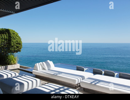 Divani e la piscina a sfioro con vista sull'oceano Foto Stock