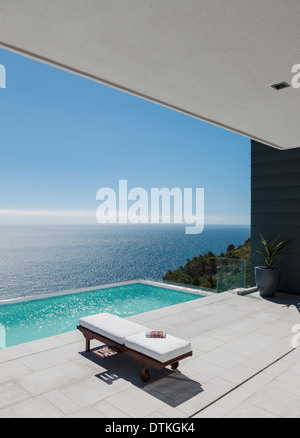 Lounge chair di piscina infinity con vista sull'oceano Foto Stock