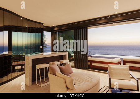 Soggiorno moderno e bar con vista sull'oceano al tramonto Foto Stock