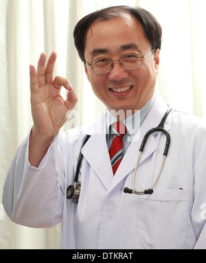 Maschio asiatici medico sorridente verso la telecamera in uniforme Foto Stock