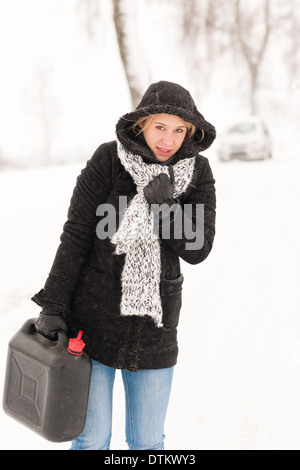 Donna che cammina con gas può auto invernale Foto Stock