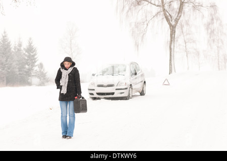 Donna che cammina con gas può auto invernale Foto Stock