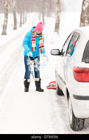 Donna in piedi sulla neve con auto catene per pneumatici Foto Stock