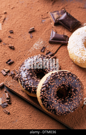 Ciambelle al cioccolato e cioccolato fondente servito sul tagliere con il cacao in polvere come sfondo. Vedere serie Foto Stock