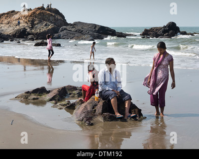 India, Goa, Vagator beach, Indiano turisti sittng sulle rocce al mare Foto Stock