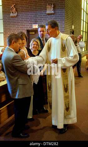 Vestita di un sacerdote cattolico saluta i genitori e i bambini durante le cerimonie di battesimo in una chiesa a Irvine, CA. Foto Stock