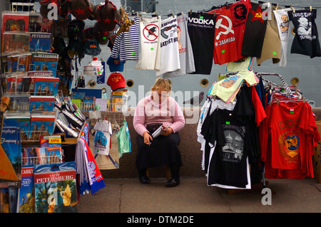 Annoiato cerca regali venditore ambulante, il fumo e la lettura di un libro. San Pietroburgo, Russia Foto Stock