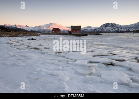 Il Boathouse da una spiaggia congelato coperto nel blocco di ghiaccio su Sommaroy vicino a Tromso, Norvegia Foto Stock