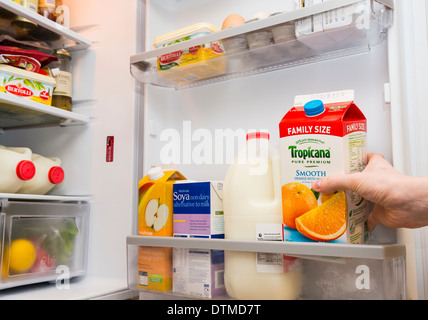 Una mano tirando fuori un cartone di Tropicana succo di arancia da una porta frigo Foto Stock