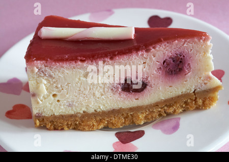 Tesco Finest Heritage lampone & swiss il cioccolato bianco cheesecake fetta su piastra di cuori impostato su sfondo rosa Foto Stock