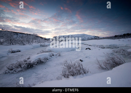 Un congelato coperto di neve fiume in montagna vicino a Tromso, Norvegia Foto Stock