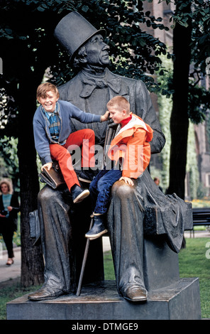 Due ragazzi di sedersi su un più grande del vita statua in bronzo di autore danese e poeta Hans Christian Andersen al di fuori del Municipio di Copenhagen, Danimarca. Foto Stock