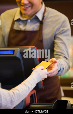 Il cliente di pagare con carta di credito in un coffee shop Foto Stock