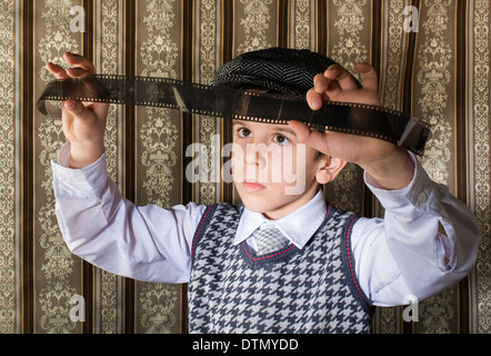 Bambino considerato analogico pellicola fotografica. Abbigliamento vintage e lo sfondo Foto Stock