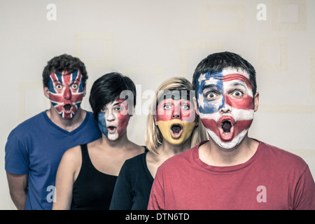 Gruppo di sorprendere le persone con bandiere dipinte sui loro volti. Foto Stock