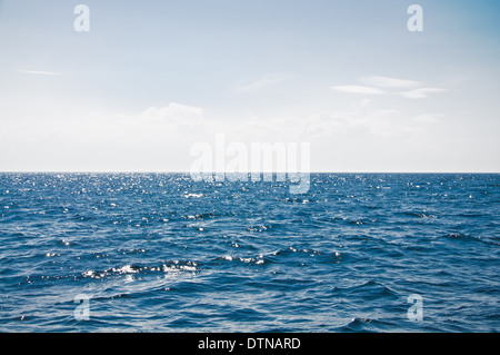 Mare blu con onde e nuvoloso cielo blu Foto Stock