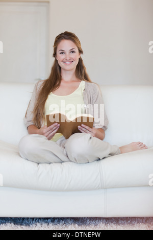 La donna gode di leggere un libro sul suo lettino Foto Stock