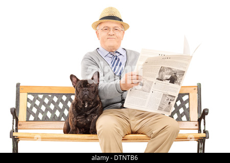 Senior gentleman seduta su una panchina con il suo cane e quotidiano di lettura Foto Stock