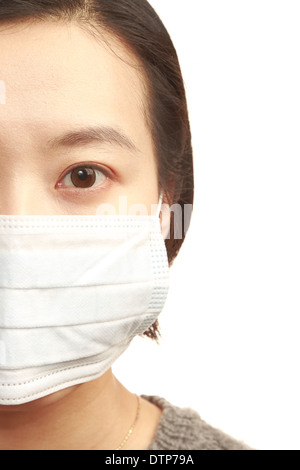 Donna asiatica che indossa la maschera per il viso su sfondo bianco Foto Stock