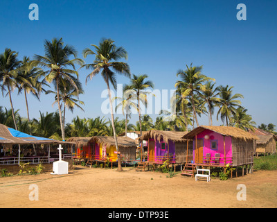 India, Goa, Morjim, colorato beach hut alloggi turistici sotto palme di cocco Foto Stock