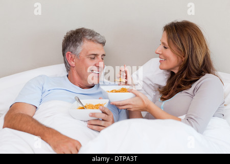 Coppia matura avente la colazione a letto Foto Stock