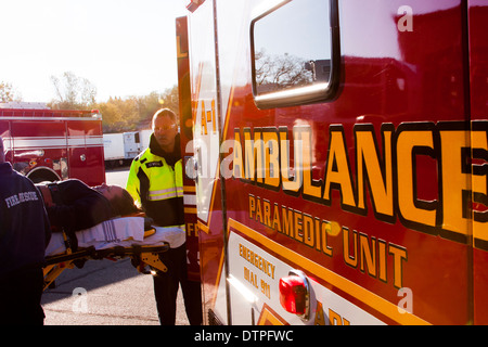 Un EMT caricamento di un paziente nella parte posteriore di un'ambulanza Foto Stock